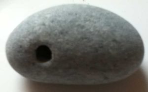 grey stone with a hole - a witch stone illustrating a children's story from Ireland’s Ballyyahoo - about a witch and her rocky beach.